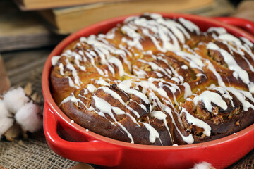 Pumpkin Cinnamon Rolls. Pumpkin buns with nuts and cinnamon, against the background of old books and yellow leaves.