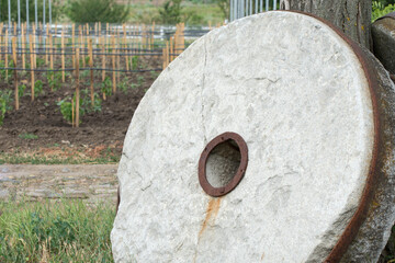 Old millstone for the mill. Large stone round millstone. - obrazy, fototapety, plakaty