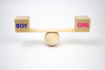 Concept of the gender of a newborn baby. Wooden blocks with the words boy and girl in blue and pink on a balanced swing on a white background.