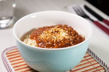 Spaghetti pasta with tomato sauce in white and blue bowl, white wooden background and resting straw plate and cutlery on the side, Brazilian cuisine copy space, top view. Food concept. Pasta concept.