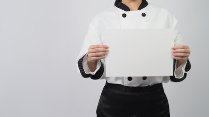 Woman wearing chef uniform and holding A4 paper on white background.