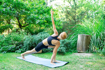 woman doing yoga in the park, young girl doing various wellness exercises, the concept of a healthy...