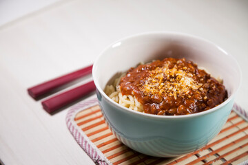 Spaghetti pasta with tomato sauce in white and blue bowl, white wooden background and resting straw plate and cutlery on the side, Brazilian cuisine copy space, top view. Food concept. Pasta concept.