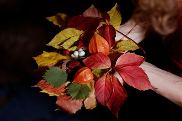 A woman holds in her hand a colorful bouquet of autumn leaves and berries. Close-up. Autumn concept.