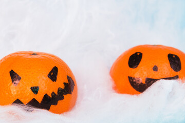 Bright orange Halloween scary tangerines emotion faces on white spider web background, selective focus