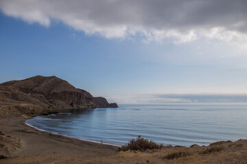 Fototapeta na wymiar small sandy cove with calm blue sea, the day is clear but clouds are entering