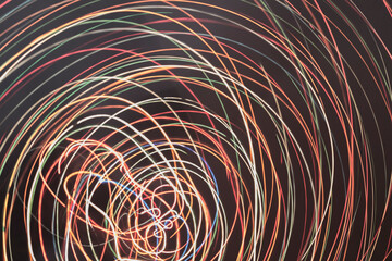 abstract background of crowd of colored lights making circles on a dark background