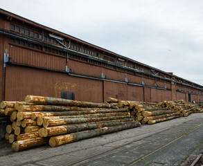 Sharpened tree trunks are stacked in front of old warehouses Pile foundations Coastal fortifications Sheds Listed Port Forwarding Dam Building materials Pile drivers