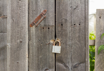 An old rusty padlock hangs on an old wooden door.