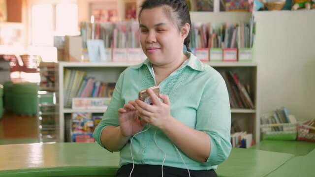 Portrait of Asian young blind person woman enjoy using smart phone with voice accessibility for persons with disabilities in creative workplace..