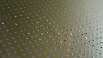 Industrial toned background in olive or bronze color. Perforated metal surface with many holes....