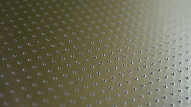 Industrial toned background in olive or bronze color. Perforated metal surface with many holes. Their ranks recede into the distance and form a perspective. Abstract aluminum backdrop or wallpaper