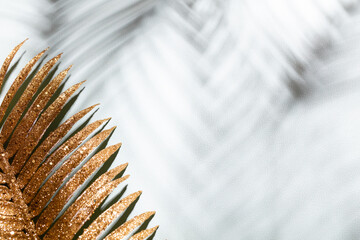 Gold palm leaves and shadows on a blue wall background.