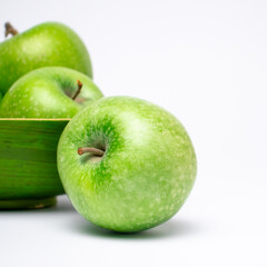 Picture of green ripe apple in wooden plate on white background.