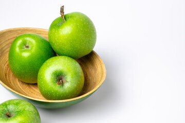 Green apples in green-brown plate on  white background. 