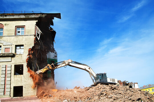excavator demolishing a brick building. Machinery Demolishing Building - Powered by Adobe