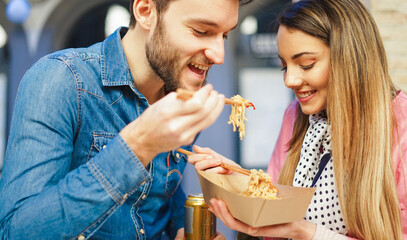 Couple of lover eating chinese food outside office - Concept of food sharing