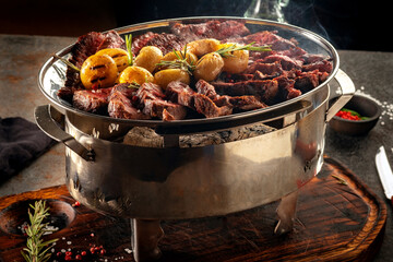 Hot grilled beef steaks on a plate with potatoes and rosemary, meat assortment