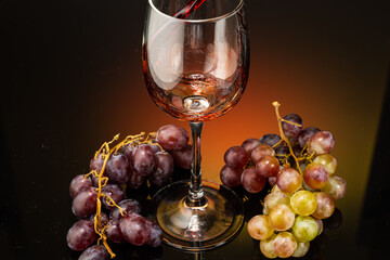 pouring red wine into a glass standing next to grapes on a gradient background