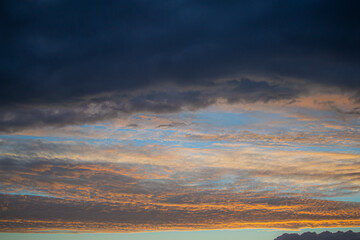 Sunset evening blue sky with orange pink and textured dark clouds