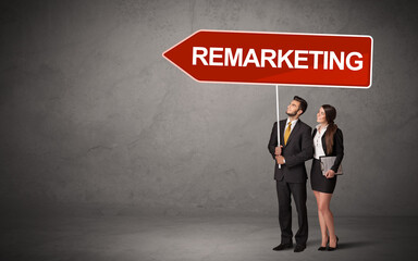 Obraz premium Young business person in casual holding road sign with REMARKETING inscription, new business direction concept