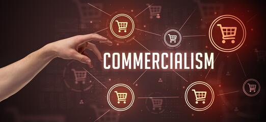 Close-Up of cropped hand pointing at COMMERCIALISM inscription, online shopping concept