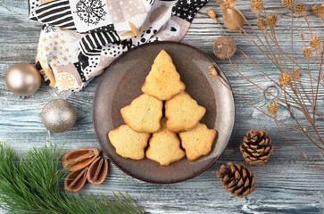 Cookies in the shape of a Christmas tree on a brown plate surrounded by cones and branches. The concept of New year and Christmas.