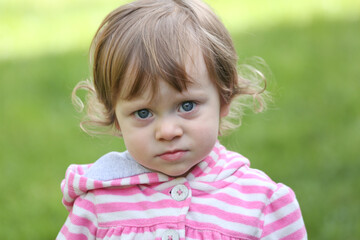 Close Up Portrait of a little 18 Month Old Girl with  Big Blue Eyes and Curly Hair, a girl Playing Outside, Funny Face Expression, Happy baby