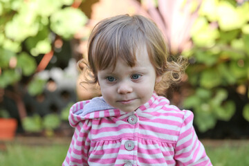 Close Up Portrait of a little 18 Month Old Girl with  Big Blue Eyes and Curly Hair, a girl Playing Outside, Funny Face Expression, Happy baby