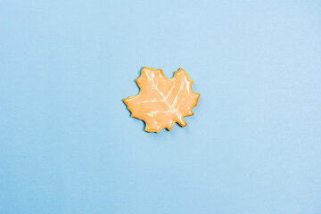 Sweet homemade leaf cookie with icing isolated on blue background minimal flat lay composition.