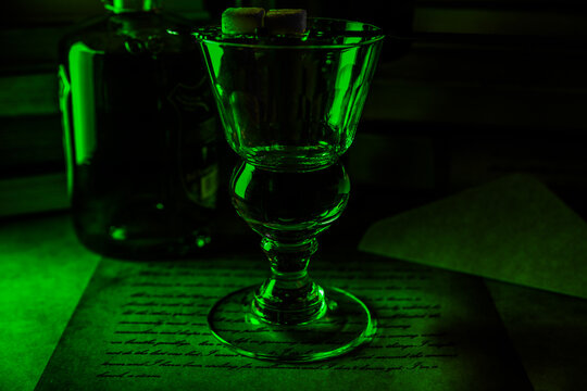 View on isolated absinth glass and bottle in gloomy green night atmosphere 