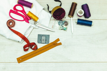 sewing tools : scissors, colorful bobbins with thread and presser foot on  wooden table