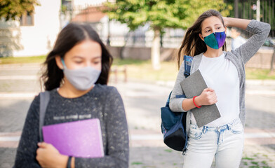 School child wearing face mask during corona virus and flu outbreak.Girls going back to school after covid-19 quarantine. Group of kids in masks for corona virus prevention.
