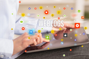 Close up of business person playing multimedia with social media icons and WEBLOGS inscription