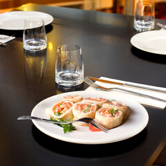 Snacks with seafood on white plate in restaurant with nobody