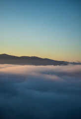 Fototapeta na wymiar Over the clouds view, mountains in the background, sunrise