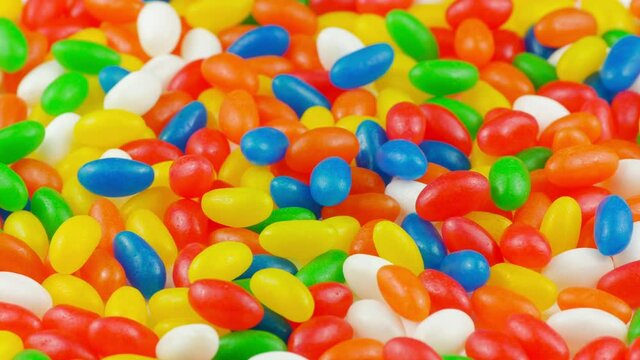 Multicolor Jelly Beans Candy Rotating Background. Bright Tasty Colourful Texture Of Blue, Green, Yellow, Red, Orange and White Sweets on Turn Table