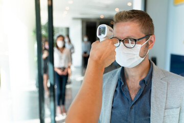 Staff check fever by digital thermometer visitor before entering the airport for scan and protect from Coronavirus