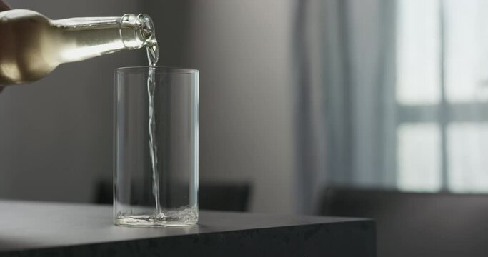 Slow motion man pour soda drink from a bottle into highball glass on concrete countertop with copy space