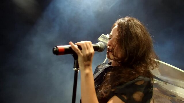 sexy performer with mic. sing a song. sensual woman singer. retro singer on stage with white piano forte. singing in microphone. pop star. professional live lead vocal performance. karaoke.