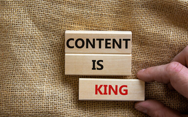 Wooden blocks form the words 'content is king' on canvas background. Male hand. Business concept.