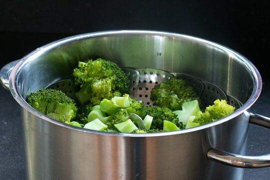 Pan filled with steamed broccolis in a dark background