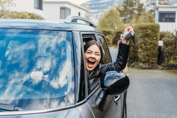 Happy young girl showing key of new car sitting inside. Excited to go to trip or journey on rental car. Freedom of traveling