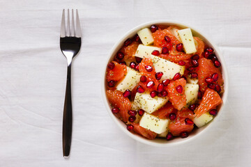 Fresh fruit salad in bowl on wooden table. Concept healthy food, diet, vegan. Flat lay, top view