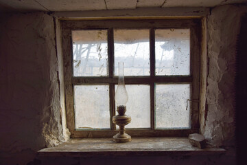 Photo of a window with a kerosene lamp on the windowsill in an old peasant house