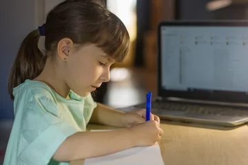 Deurstickers Online onderwijs op afstand. Klein schoolmeisje studeert thuis. © Albert Ziganshin