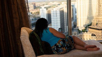 Beautiful Biracial, multiracial woman sits on chase in hotel room in business suit