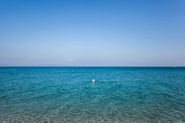 Fototapeta na wymiar Woman wearing summer hat swimming in a sea, Kos island, Greece