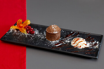 Chocolate homemade bundt cake. A wonderful sweet dessert bundt cake with a piece of ice cream on a black plate in the original setting.