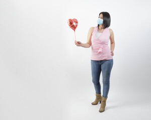 woman wearing mask in studio looking a red balloon heart